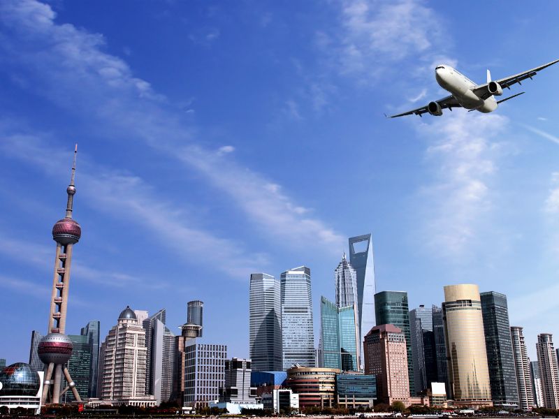 上海の街中の上空を飛ぶ飛行機のイメージ