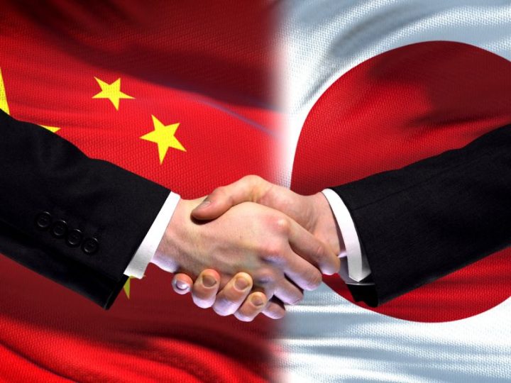 中国国旗と日本国旗の前でビジネスマンが握手している画像