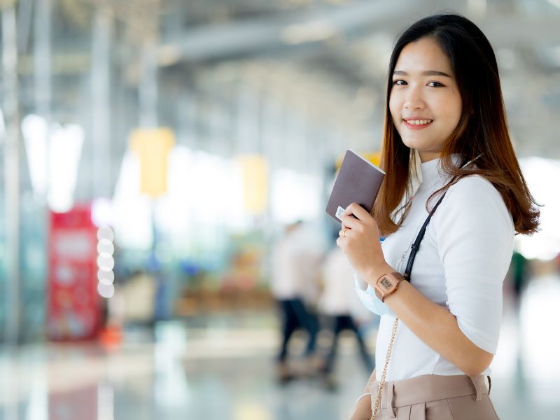 中国人女性が空港でパスポートを手にしている画像