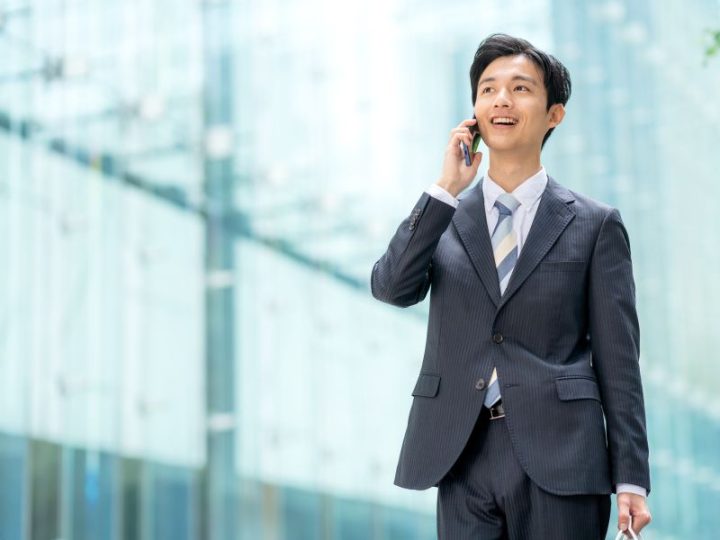 ビジネスマンがオフィス街で歩きながら電話している画像