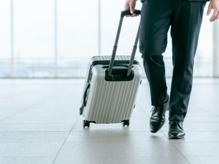 商社マンが空港でスーツケースを引きながら歩いている画像